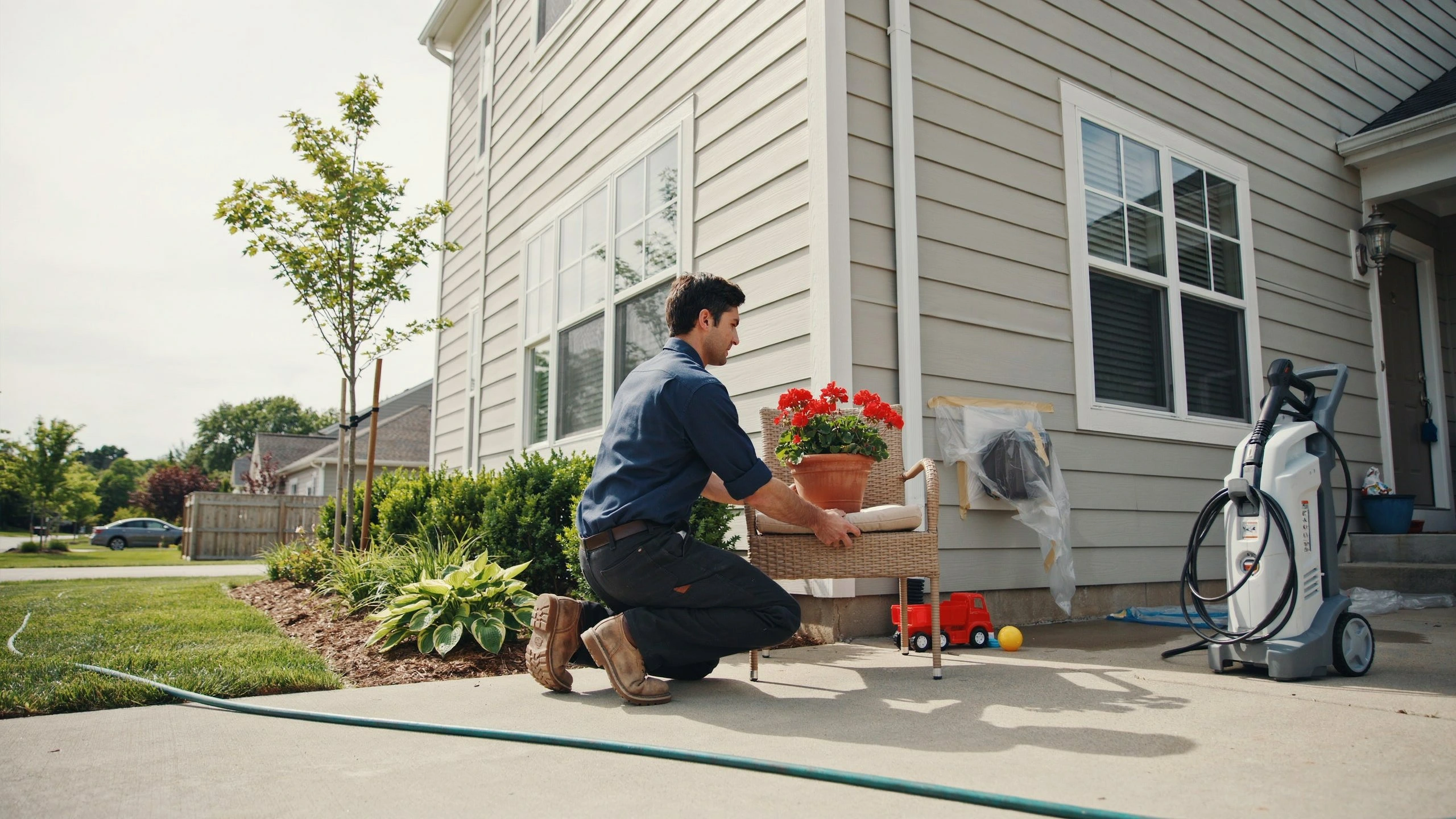 Bay SoftWash technician moving patio chair with flowers before pressure washing a North Bay Ontario home